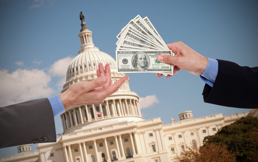 Two male hands in suits, exchanging a bribe in front of the US Capitol